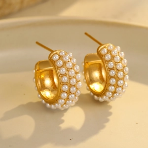 Macro shot of 18K gold-plated C-shaped earrings featuring elegant inlaid white pearls