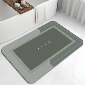 Close-up of a grey-green diatom mud bathroom mat with HOME text on marble floor