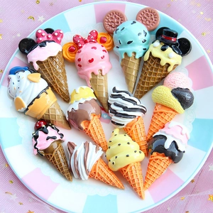 Flat back resin ice cream cones in assorted colors arranged on a striped porcelain plate