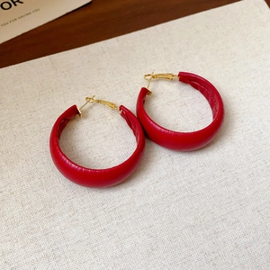 Detail of red leather textured round hoop earrings with elegant gold metal pins
