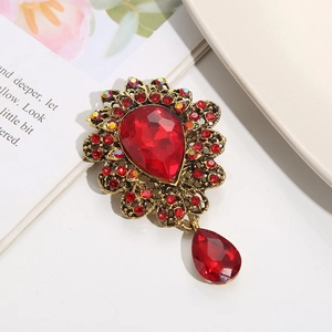 Detailed close-up of a vintage crystal brooch with a red teardrop gemstone and gold setting