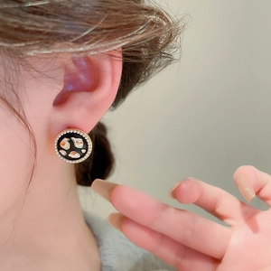 Close-up of vintage round earrings with black enamel, leopard print, and tiny pearls