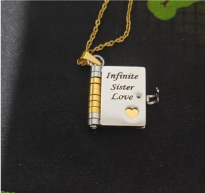 Macro view of book-shaped pendant engraved with Infinite Sister Love on silver and gold metal