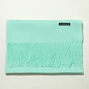Close-up of the light blue cashmere scarf showing soft texture and tassel details