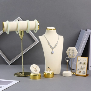 Beige velvet and gold metal jewelry display set featuring necklace busts and ring stands