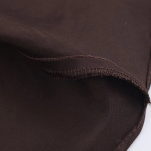 Macro shot of dark brown satin midi dress fabric with twill texture and overlock stitching