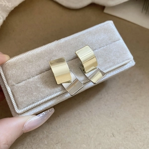 Detail view of two-tone square curved metal earrings in a soft grey jewelry box