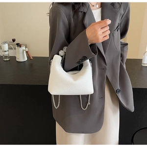 Detailed view of mini white textured handbag with silver chain and elegant pearl handle