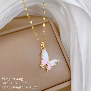 Detailed macro of gold butterfly pendant with pink enamel and zircons on silk background