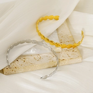 Detailed close-up of gold and silver heart-shaped open bangles on a travertine stone