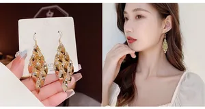 Detailed view of long gold tassel earrings with layered metal leaves and white rhinestones