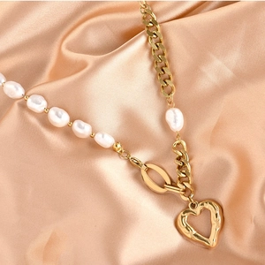 Elegant gold titanium necklace featuring irregular pearls and a heart pendant on silk