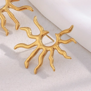 Retro 18K gold plated stainless steel sunburst stud earrings on soft fabric background