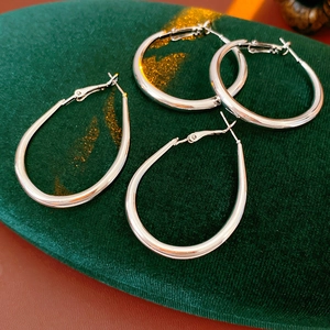 Close-up of silver geometric U-shaped hoop earrings on dark green velvet padding