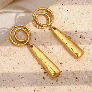 Gros plan sur boucles d'oreilles pendantes dorées 18K en acier martelé sur pierre