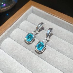 Macro detail of silver C-shaped earrings with blue resin stars in a velvet box