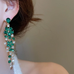Close-up of elegant flower tassel earrings with green gemstones and sparkling diamond accents