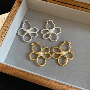 Close-up of gold and silver flower earrings with hammered metal texture and pearl centers