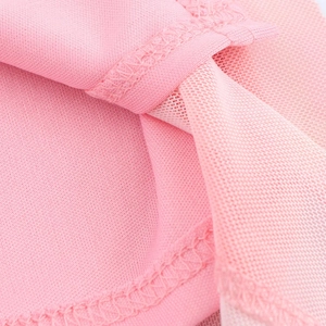 Gros plan sur le tissu en maille rose montrant la texture hexagonale fine et la couture