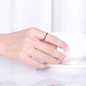 Detailed view of a minimalist rose gold titanium ring on finger with polished finish