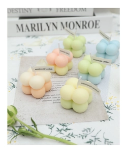 Detailed close-up of handmade cube bubble candles in assorted pastel colors on a floral cloth