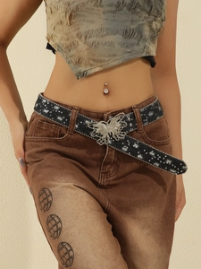 Detail of a black canvas belt featuring a sparkling silver butterfly buckle and navel ring