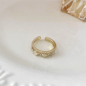 Dettaglio anello a corona placcato oro con zirconi e opale bianco su piatto di ceramica