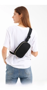 Detail of black mini waist bag worn on back with adjustable strap and golden zipper