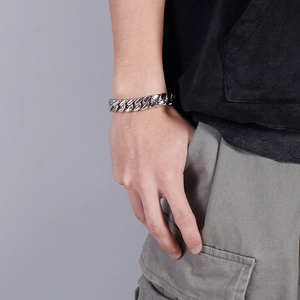 Close-up of a 12mm silver stainless steel Cuban link bracelet worn on a male model's wrist