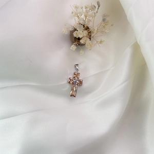 Macro view of silver cross pendant with champagne crystals on white silk background