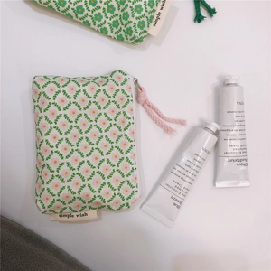 Detail view of floral canvas coin pouches in pink and green with woven zipper pulls