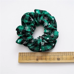 Christmas hair scrunchie with green plaid snowflake pattern next to a wooden ruler