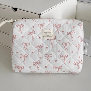Close-up of quilted cosmetic bag with pink bow floral patterns and small fabric label