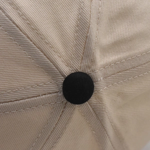 Macro shot of cotton baseball cap crown with beige twill fabric and black top button detail