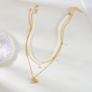 Detail of layered gold necklace with white pearls, seashell and starfish charms