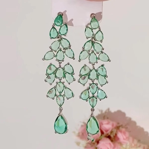 Detail of silver needle long teardrop tassel earrings with light green zircons