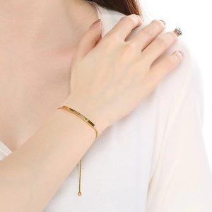 Gold LOVER DREAM engraved bar bracelet with adjustable chain on model's wrist