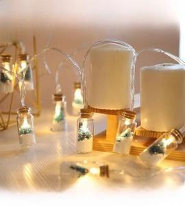 Close-up of LED glass wishing bottle lights with mini Christmas tree and artificial snow