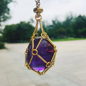 Detailed shot of purple amethyst stone in gold metal mesh pendant on bamboo chain