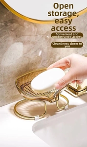 Detail of amber leaf-shaped soap dish with gold metal stand on marble surface