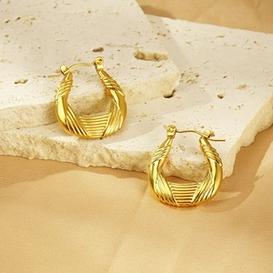 Detailed close-up of 18k gold U-shaped earrings with spiral textured finish on stone
