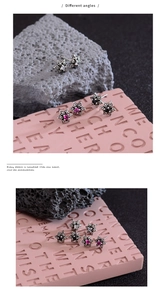 Macro shot of silver star stud earrings with colorful zircon stones on stone background