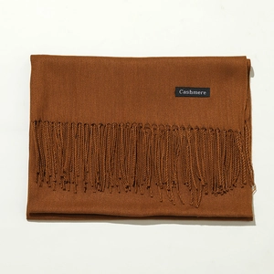 Detailed texture of brown cashmere scarf with classic tassel trim on white background