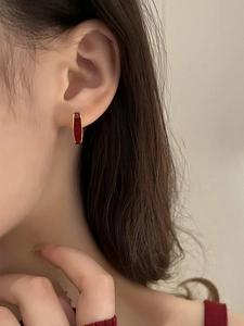 Close-up of elegant red drip glaze oval earrings worn by a model in a luxury style