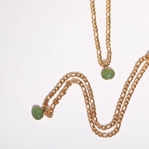 Detailed shot of green aventurine stone pendants on gold Figaro chain necklaces