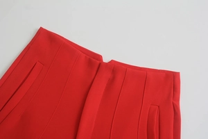 Dettaglio dei pantaloni rossi a vita alta con cuciture a vista e tasche funzionali