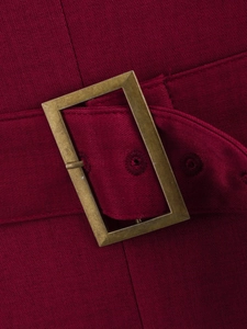 Macro detail of wine red woven fabric and vintage gold buckle on a tailored blazer