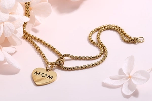 Detail of gold heart pendant with MOM engraving on double layer pearl chain