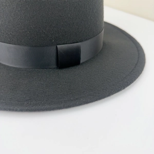 Detail of the black wool felt flat top fedora hat featuring a grosgrain ribbon texture