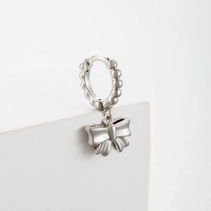 Silver bow-knot hoop earrings with zircon stones on a white minimalist display stand